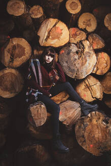 Porträt einer jungen Frau an einem Holzstapel - DAMF00115