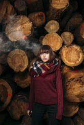 Porträt einer jungen Frau an einem Holzstapel - DAMF00117