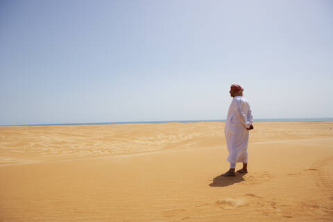 Beduine in Nationaltracht in der Wüste stehend, Rückansicht, Wahiba Sands, Oman, lizenzfreies Stockfoto