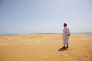 Beduine in Nationaltracht in der Wüste stehend, Rückansicht, Wahiba Sands, Oman - WWF05293