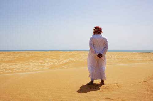 Beduine in Nationaltracht in der Wüste stehend, Rückansicht, Wahiba Sands, Oman - WWF05294