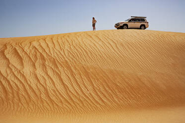 Mann steht in der Wüste, neben Geländewagen, Wahiba Sands, Oman - WWF05297