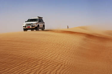 Man taking pictures in the desert, next to off-road vehicle, Wahiba Sands, Oman - WWF05310