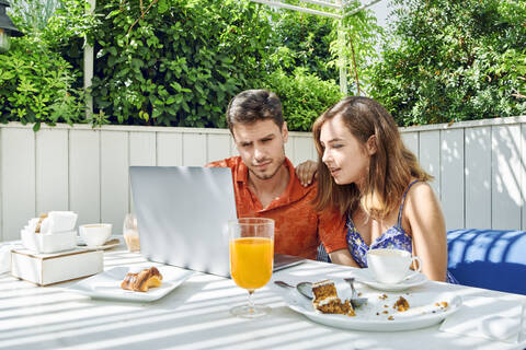 Junges Paar benutzt Laptop beim Frühstück, lizenzfreies Stockfoto