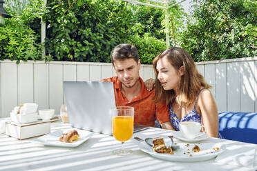 Young couple using laptop during breakfast - JNDF00112