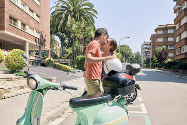 Junges Paar küsst sich auf einem Oldtimer-Motorroller - JNDF00115