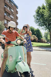 Young couple standing at vintage motor scooter - JNDF00117