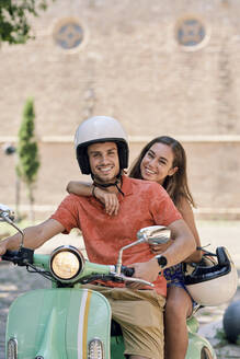 Portrait of a smiling young couple on a vintage motor scooter - JNDF00124