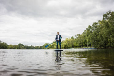 Geschäftsmann beim Stand Up Paddling auf einem See - JOSF03781