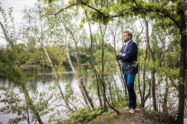 Businessman at lakeshore looking out - JOSF03789