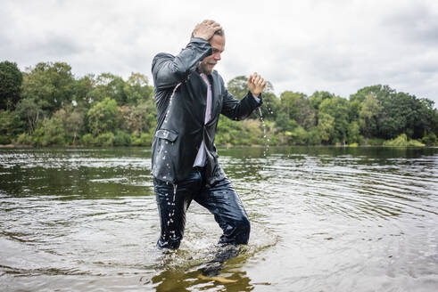 Wet businessman walking in a lake - JOSF03801