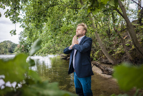 Businessman standing in a lake meditating - JOSF03813