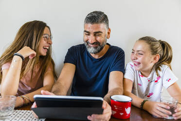 Glücklicher Vater mit zwei Töchtern, die zu Hause ein Tablet benutzen - MGIF00704