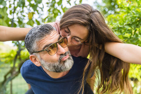 Vater trägt Tochter huckepack im Garten, lizenzfreies Stockfoto