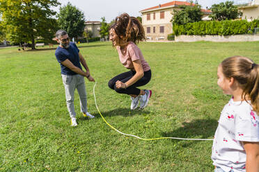 Father with daughter holding rope for girl skipping - MGIF00738