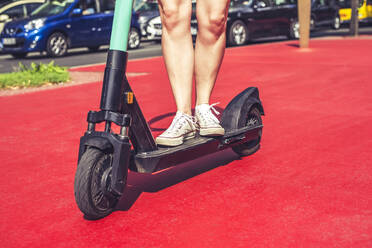 Beine einer jungen Frau auf einem E-Scooter auf dem Boulevard der Stars, Berlin, Deutschland - BFRF02091