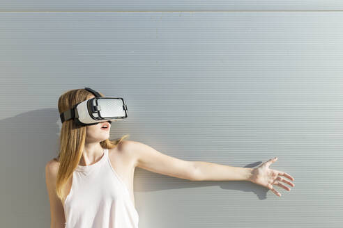 Young woman using Vr googles, reaching with her hand - JPTF00327