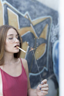 junge Frau zündet sich eine Zigarette mit einer Wunderkerze an - JPTF00336