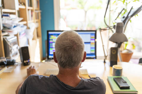 Älterer Mann arbeitet im Büro und benutzt einen Computer, lizenzfreies Stockfoto