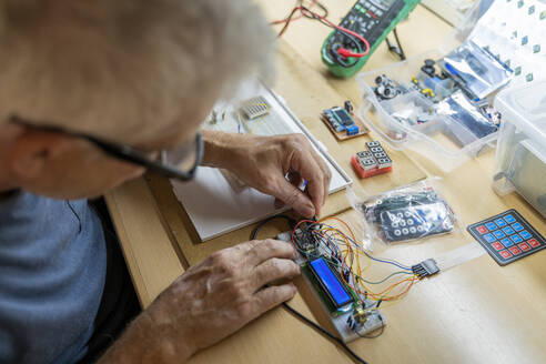 Ein älterer Mann arbeitet an elektronischen Schaltkreisen in seiner Werkstatt - AFVF04010