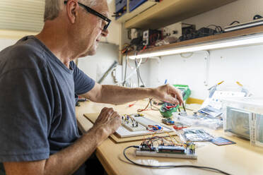 Senior man working on electronic circuits in his workshop - AFVF04013
