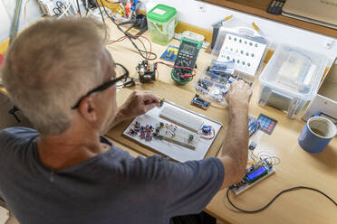 Senior man working on electronic circuits in his workshop - AFVF04014