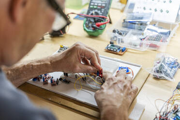 Ein älterer Mann arbeitet an elektronischen Schaltkreisen in seiner Werkstatt - AFVF04015