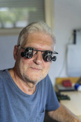 senior man wearing magnifying specracles, portrait stock photo