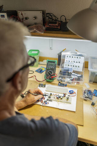 Senior man working on electronic circuits in his workshop stock photo