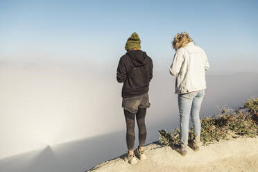 Young women with respirator masks standing at the edge of volcano Ijen, Java, Indonesia - KNTF03602