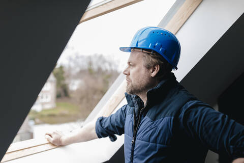 Architekt schaut aus dem Fenster auf einer Baustelle, lizenzfreies Stockfoto