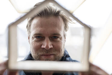 Architect looking through wooden house model - GUSF02662