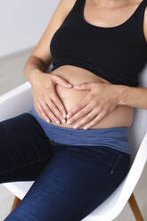 Young pregnant woman sitting on chair - HMEF00601