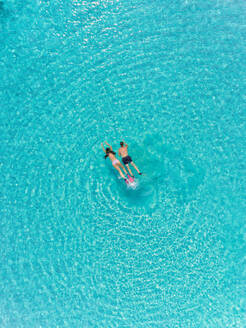 Luftaufnahme eines Mannes und einer Frau mit Masken und Flossen beim Schnorcheln in türkisfarbenem Wasser. - AAEF03653
