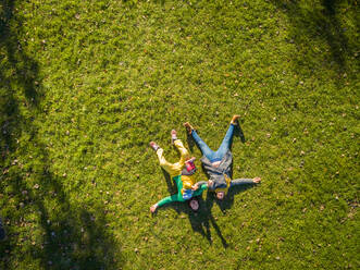 Aerial view of family laying down on grass at public playground, Zagreb. - AAEF03750