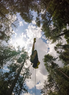 Luftaufnahme einer Person, die den Wald durch ein großes Seilbahnseil in Slowenien durchquert. - AAEF03891