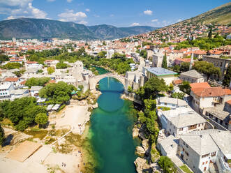 Luftaufnahme von Menschen, die die Alte Brücke über den Fluss Neretva in Mostar, Bosnien und Herzegowina, überqueren. - AAEF03932