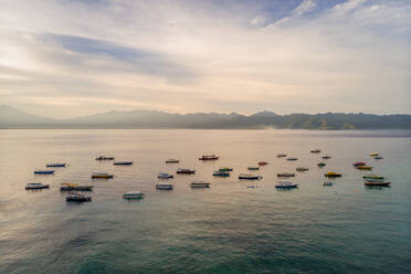 Luftaufnahme einer Gruppe von Booten, die während des Sonnenuntergangs neben der Insel Gili Trawangan vor Anker liegen. - AAEF04304