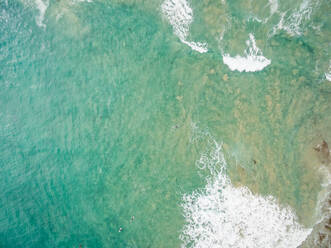 Luftaufnahme von Menschen beim Surfen an der Küste Australiens in der Ferne. - AAEF04393