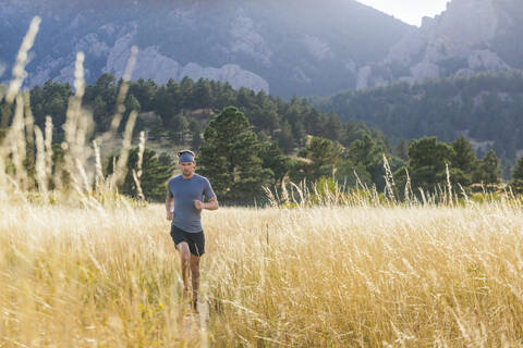 Mann läuft durch hohes Gras auf dem Bear Canyon Trail in Boulder, Colorado, lizenzfreies Stockfoto