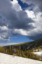 Man trail runs on snow in Indian Peaks Wilderness, Colorado - CAVF63402