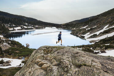 Mann läuft auf Felsen über einen See in der Indian Peaks Wilderness, Colorado - CAVF63406