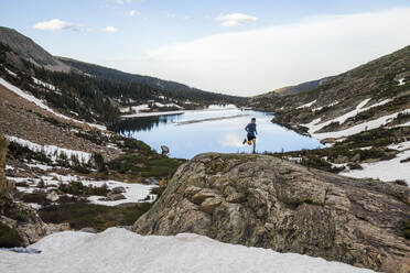 Mann läuft auf Felsen über einen See in der Indian Peaks Wilderness, Colorado - CAVF63407