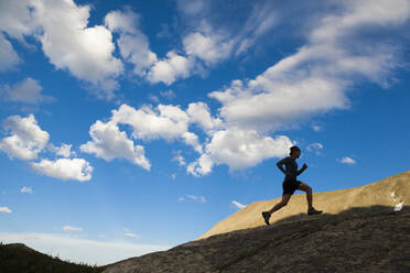 Man runs up rock as silhouette in Indian Peaks Wilderness, Colorado - CAVF63408