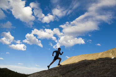 Man runs up rock as silhouette in Indian Peaks Wilderness, Colorado - CAVF63412