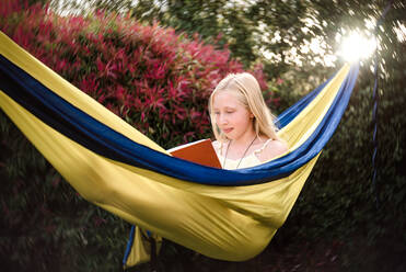 Adolescent girl reading in a yellow hammock - CAVF63471