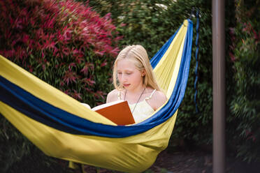 Preteen girl in hammock with a book - CAVF63472