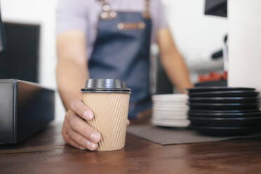 Junger Besitzer eines Kaffeehauses, der Kunden bedient. - CAVF63517