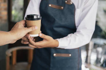 Junger Besitzer eines Kaffeehauses, der Kunden bedient. - CAVF63518