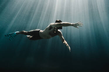 Ein Mann schwimmt in voller Länge unter Wasser im Ozean - CAVF63536